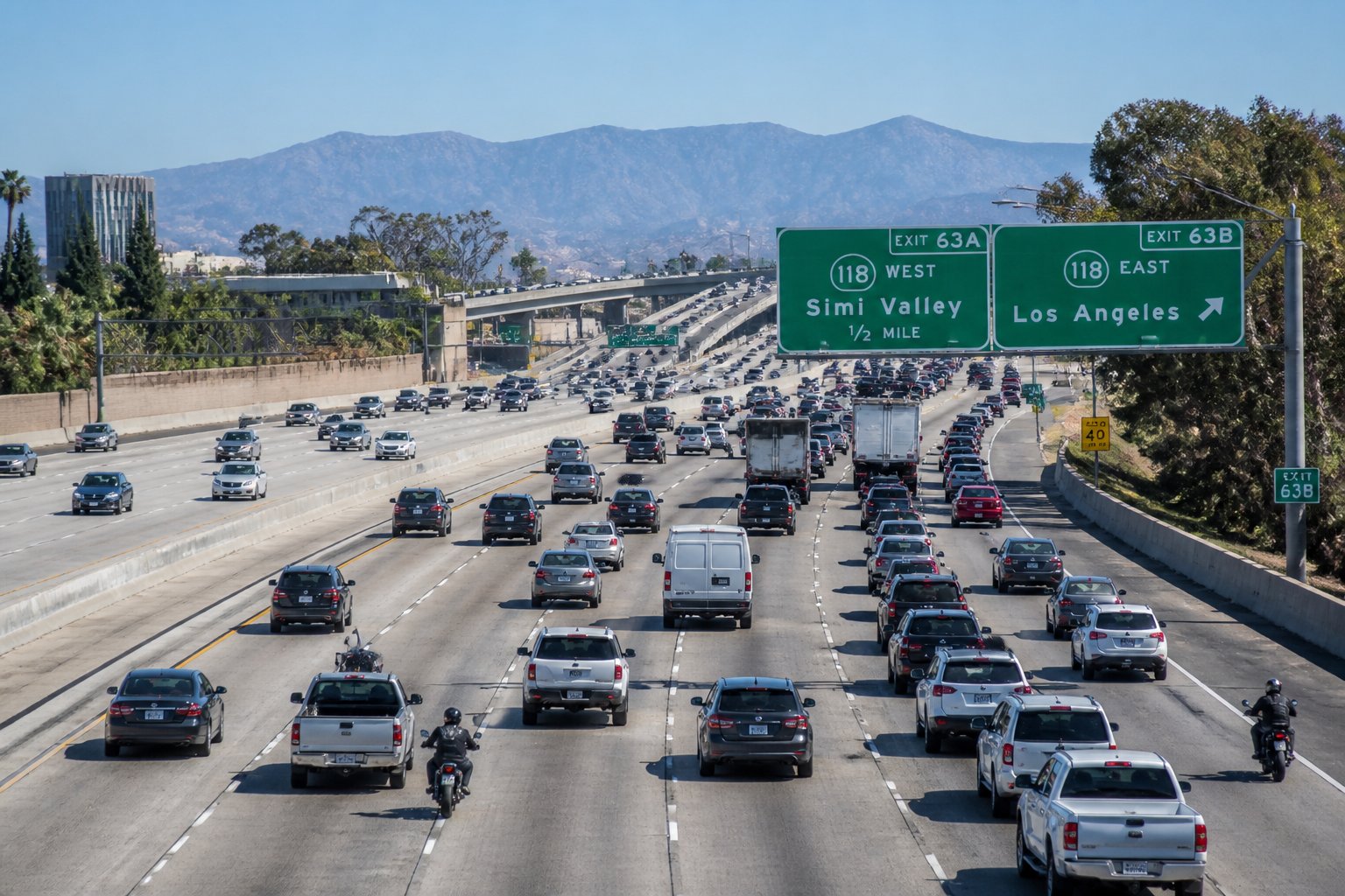 A busy section of the 118 Freeway with multiple vehicles driving on several lanes under clear skies.